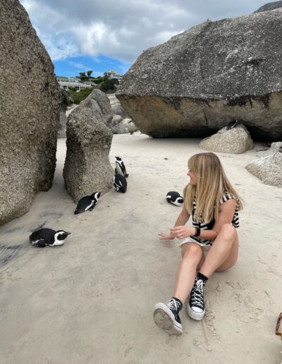 girl sitting next to cape town penguins